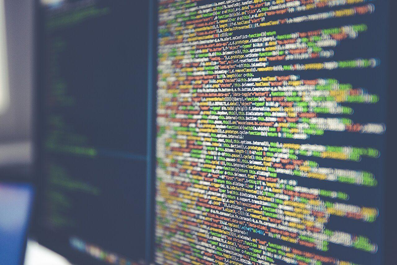 Colourful code displayed across two computer monitors