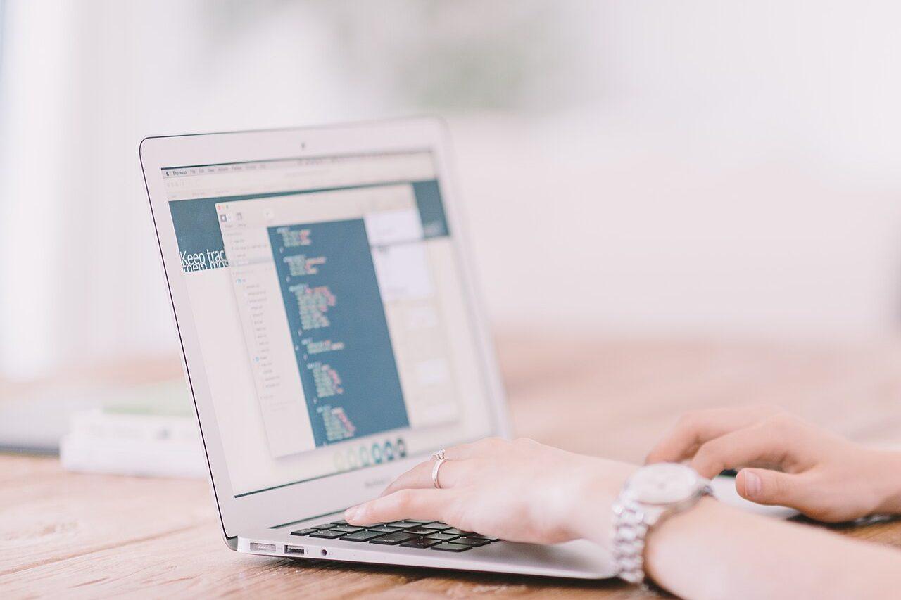 Hands typing code on a laptop keyboard